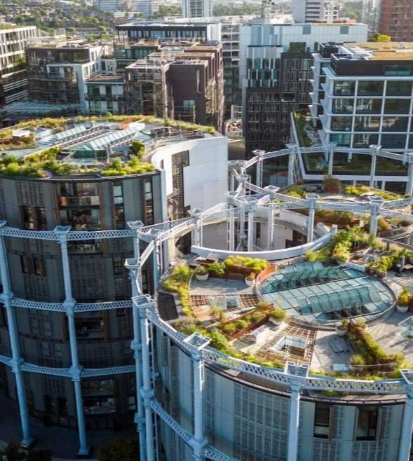 Aerial view of modern office buildings with landscaped rooftop gardens and sustainable green roof terraces in an urban business district.